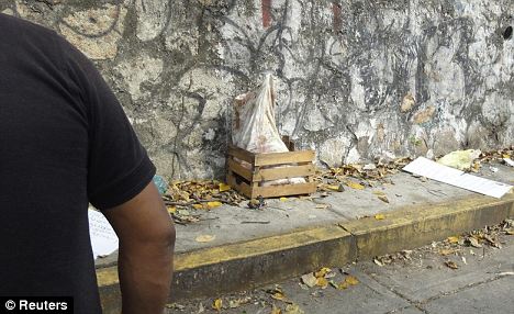 A police officer in Acapulco stands next to the sack containing five severed heads which has been placed in a small wooden crate
