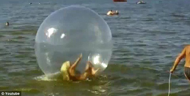 For two minutes the woman can be seen flapping about in the water sphere and even appears to head butt the soft side of the bubble, desperate to get back on her feet