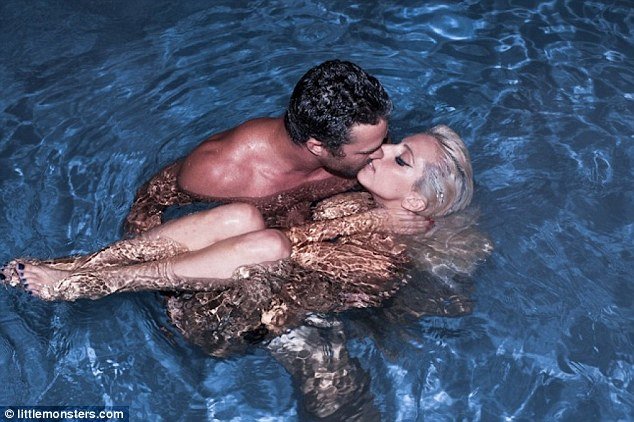 Lady Gaga appears to be skinny-dipping with her boyfriend Taylor Kinney as he embraces her for a passionate kiss in the water