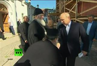 Vladimir Putin reacts awkwardly as a priest bows to kiss his hand during a visit to country's northern Valaam Island