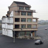 Luo Baogen and his wife insist on living in the half-demolished building because they believe that the relocation compensation offered by the government is not enough.