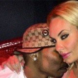 Coco Austin smirking at the camera and wrapping her arm around AP.9 as he plants a kiss on her cheek and burrows his face in her neck