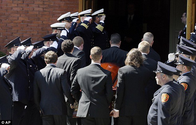 Firefighters honor guard salute as pallbearers carry the casket of Boston Marathon bomb victim Krystle Campbell into St Joseph's Church for her funeral in Medford 