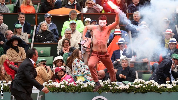 Masked protester waving a lit flare ran onto the court at the men's final of the French Open tennis in Paris
