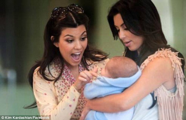 Kim Kardashian posted a Facebook picture of herself and sister Kourtney cooing over a new born baby