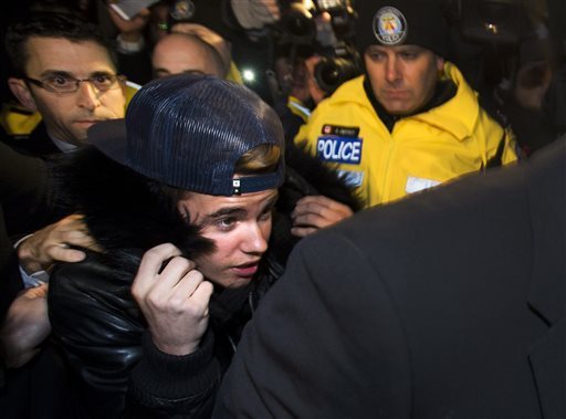 Justin Bieber handed himself in at a Toronto police station where he was mobbed by TV crews, news photographers and screaming teenage fans